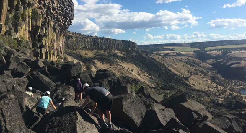 a small group of students navigate large rocks on an outward bound course